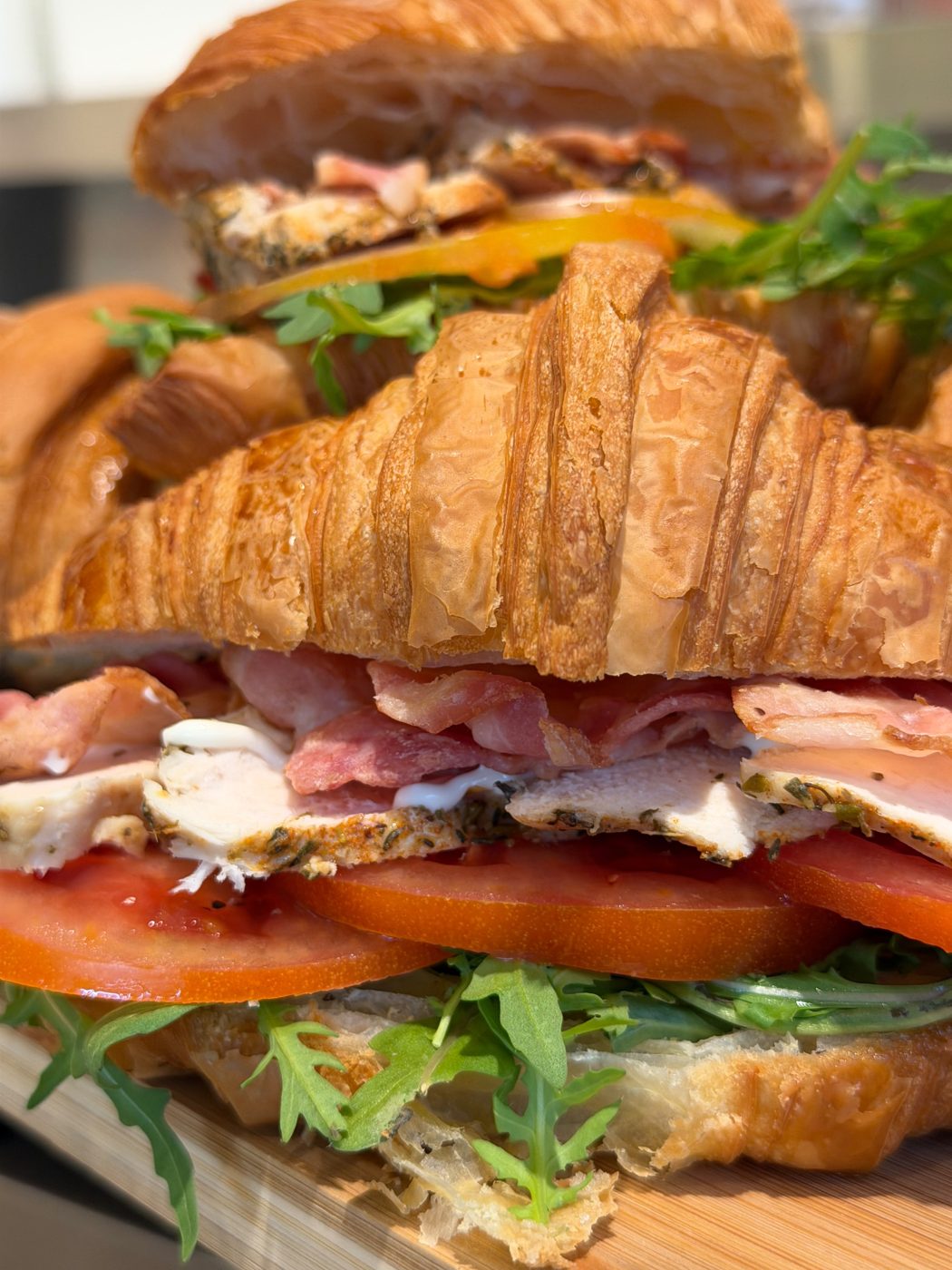 Croissant club sandwich stacked with ham, cheese and rocket