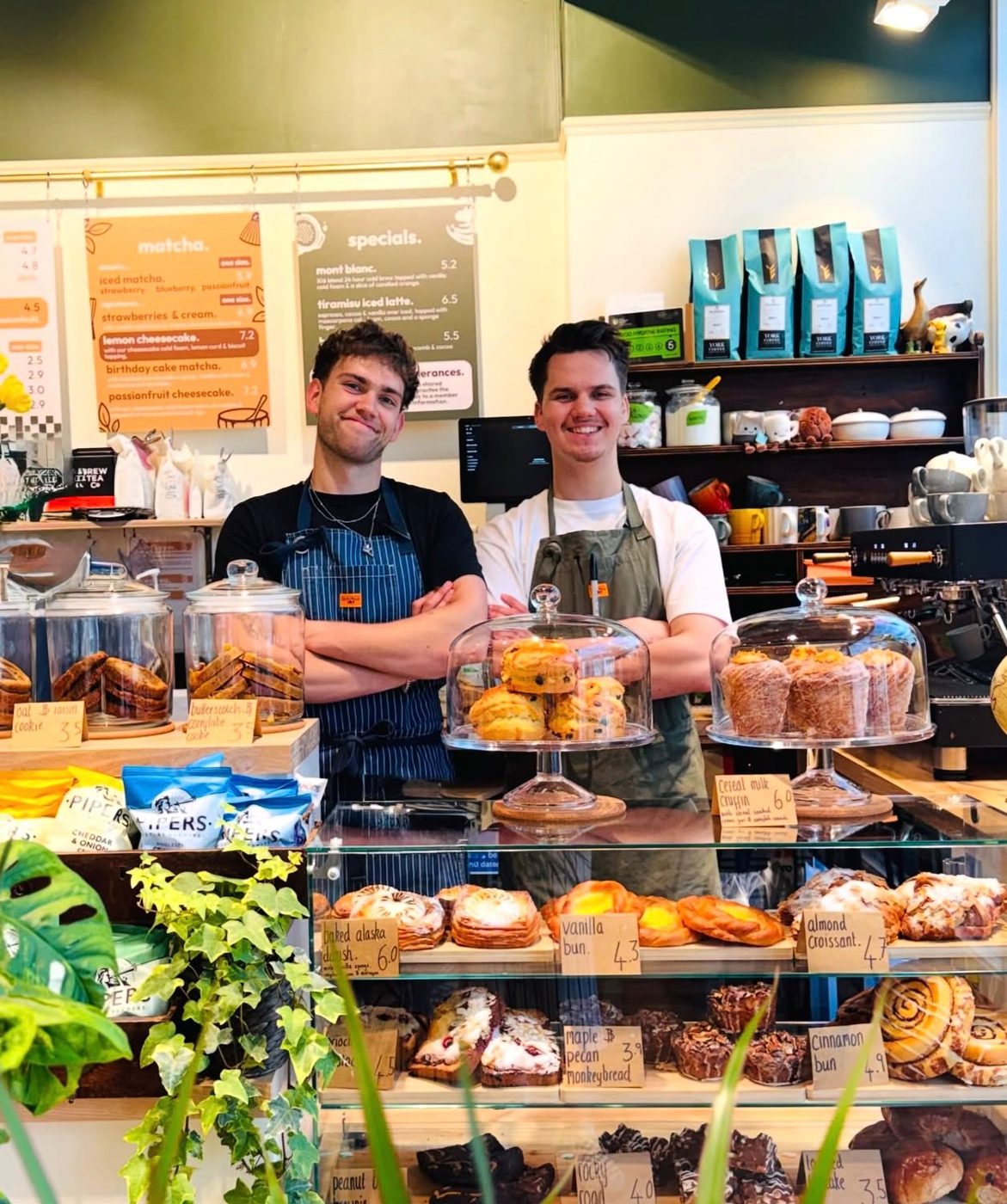 George and Olly, founders of brew'd, smiling behind the counter