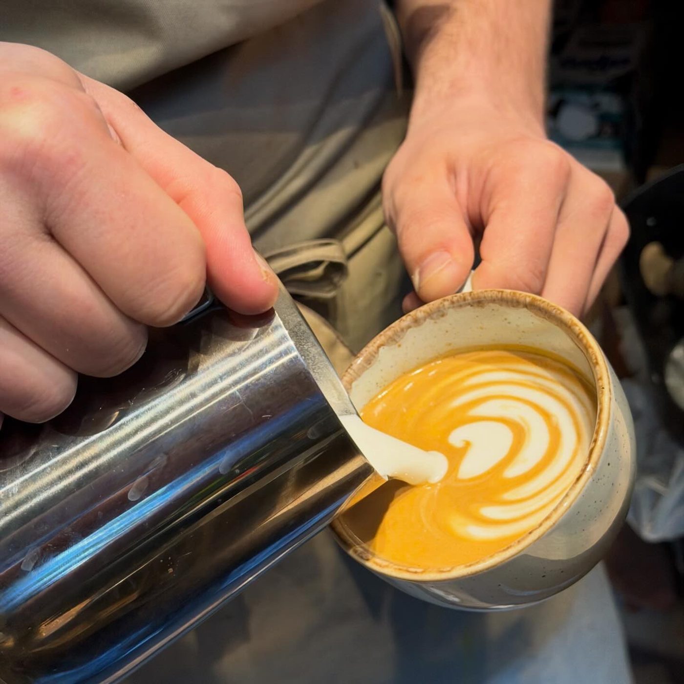 Latte art being poured into a brew'd cup