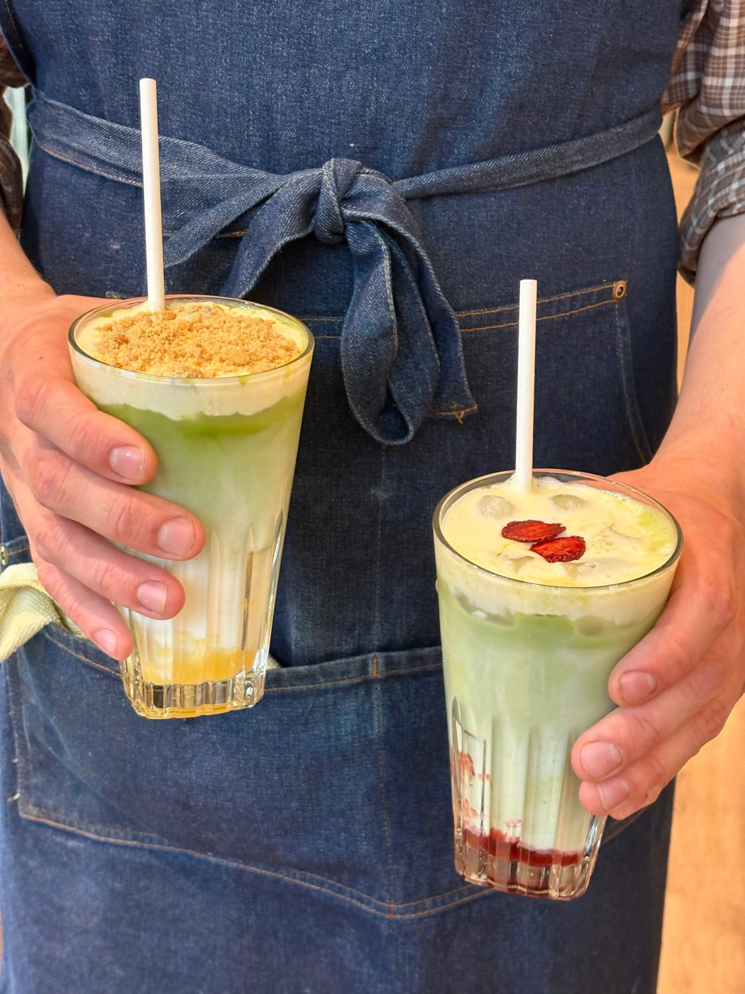 Two iced signature matchas held behind the counter